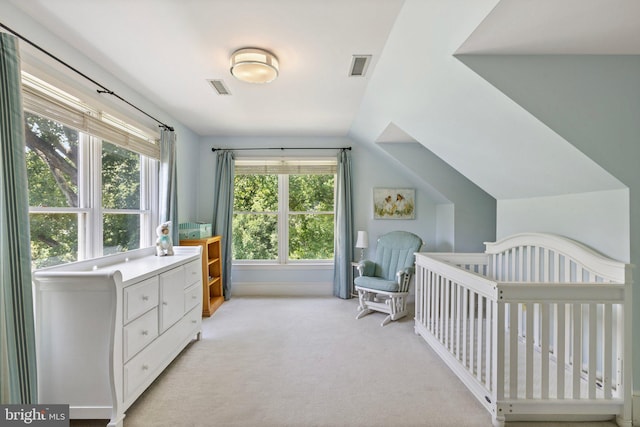 carpeted bedroom featuring multiple windows, vaulted ceiling, and a crib