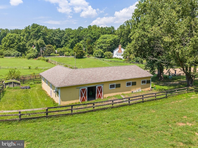 view of front of home featuring an outdoor structure, a front yard, and a rural view