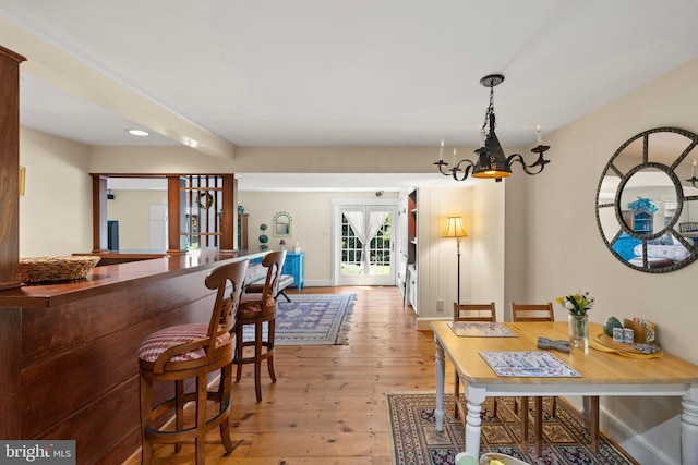 dining room with an inviting chandelier, bar, and light hardwood / wood-style flooring