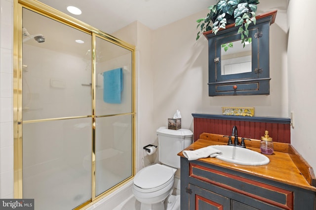 bathroom with a shower with door, vanity, and toilet