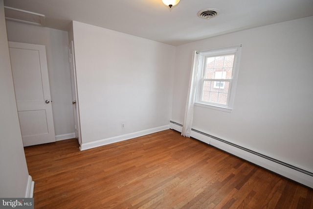 empty room featuring baseboard heating and light hardwood / wood-style flooring