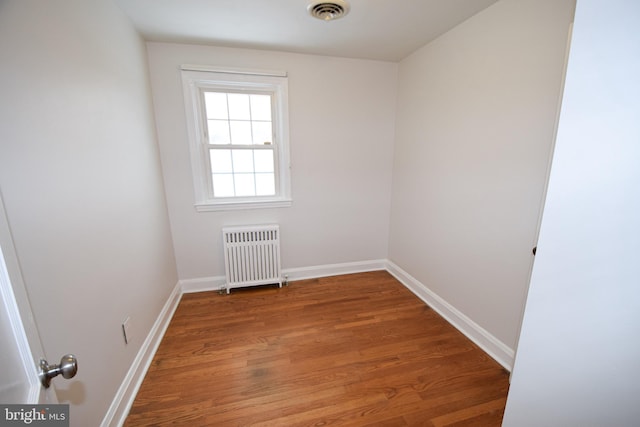 spare room featuring radiator and hardwood / wood-style floors