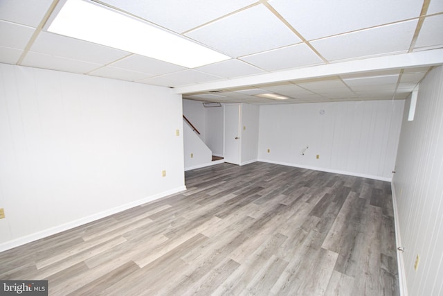 basement with a drop ceiling and wood-type flooring