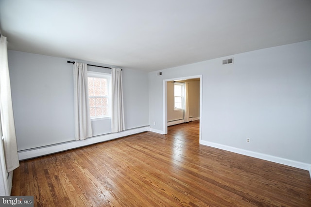 spare room featuring a baseboard heating unit and hardwood / wood-style floors