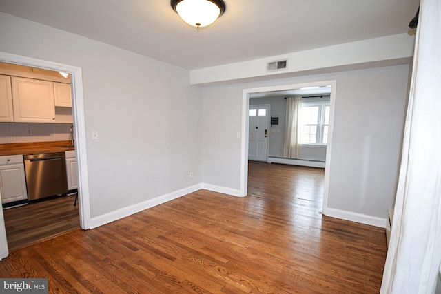 unfurnished dining area with dark wood-type flooring and a baseboard heating unit