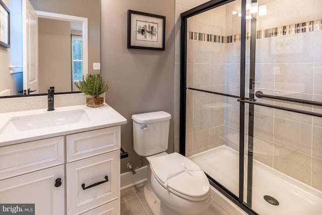 bathroom with tile patterned floors, toilet, a shower with door, and vanity