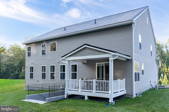 rear view of house featuring a wooden deck and a lawn