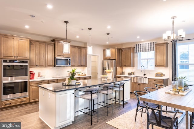 kitchen featuring decorative light fixtures, appliances with stainless steel finishes, sink, and a center island