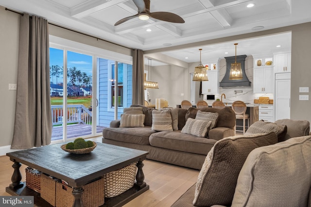 living room with coffered ceiling, light hardwood / wood-style flooring, beamed ceiling, and ceiling fan