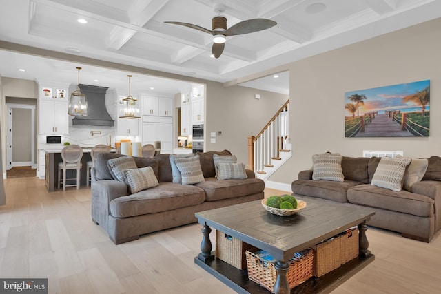 living room with crown molding, light wood-type flooring, beam ceiling, ceiling fan with notable chandelier, and coffered ceiling