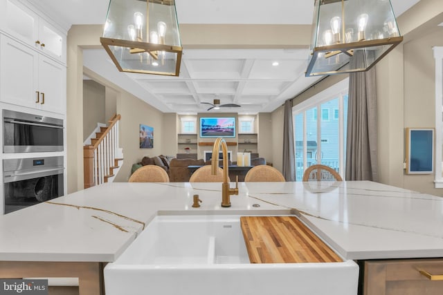 kitchen featuring decorative light fixtures, white cabinetry, stainless steel oven, and coffered ceiling