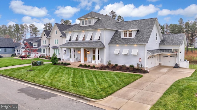 view of front of house featuring covered porch, a garage, and a front lawn