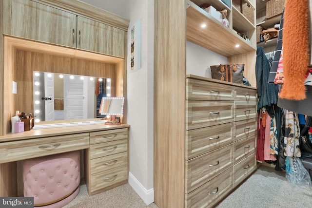 walk in closet featuring light carpet and built in desk