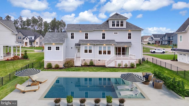 rear view of house with a fenced in pool, a patio, and a yard