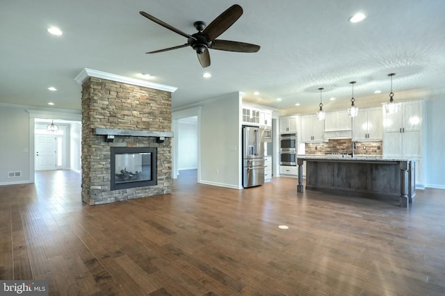 unfurnished living room with ceiling fan, dark hardwood / wood-style floors, crown molding, and a stone fireplace