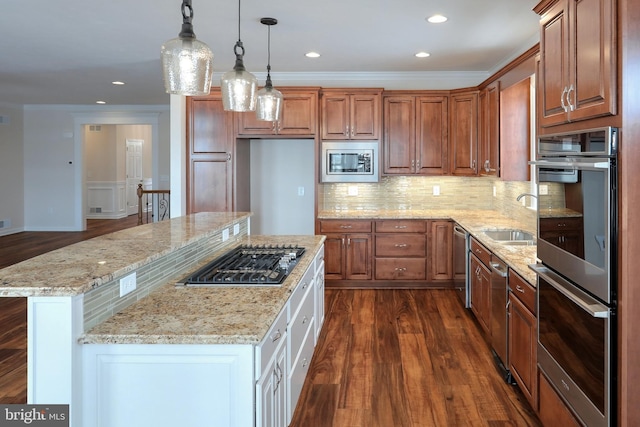 kitchen with appliances with stainless steel finishes, dark hardwood / wood-style floors, light stone countertops, a kitchen island, and sink