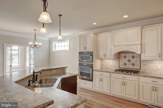 kitchen featuring stainless steel gas stovetop, decorative light fixtures, sink, and cream cabinets