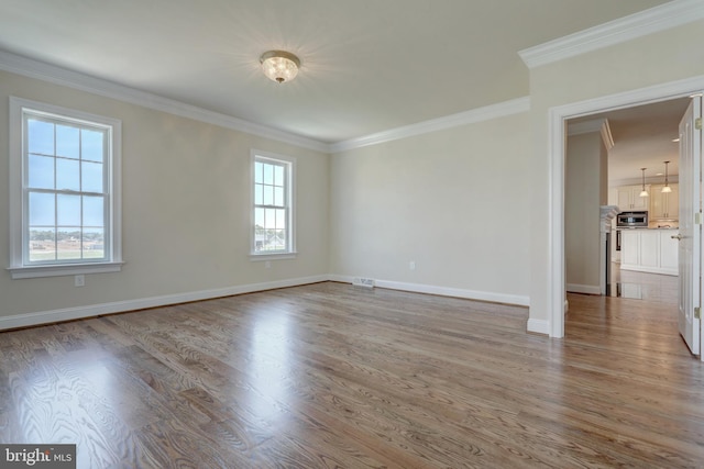 spare room with ornamental molding and light hardwood / wood-style floors