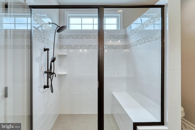 bathroom featuring a shower with shower door and toilet