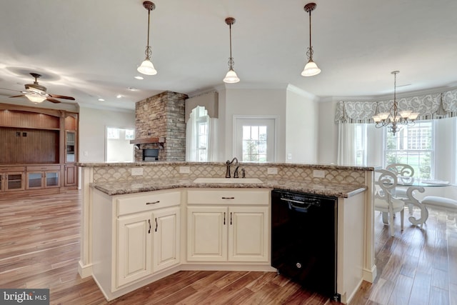 kitchen with black dishwasher, pendant lighting, a kitchen island, and sink