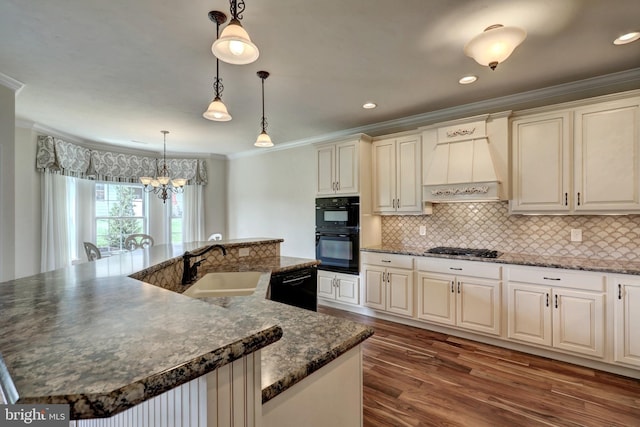 kitchen featuring decorative light fixtures, a spacious island, black appliances, and sink