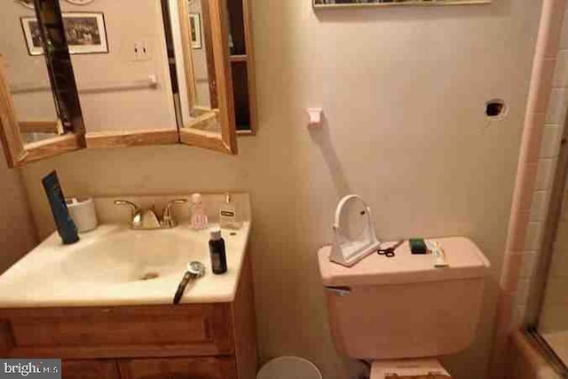 bathroom featuring toilet, an enclosed shower, and vanity