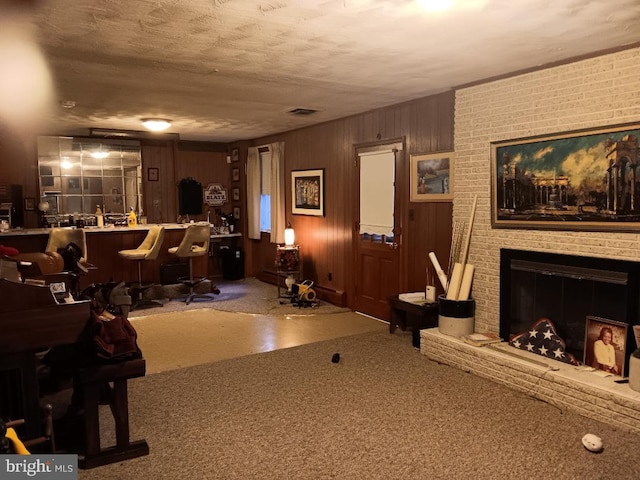 living room with a textured ceiling, wooden walls, bar, and a fireplace