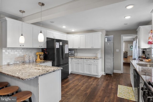 kitchen featuring black appliances, light stone countertops, white cabinetry, pendant lighting, and a breakfast bar