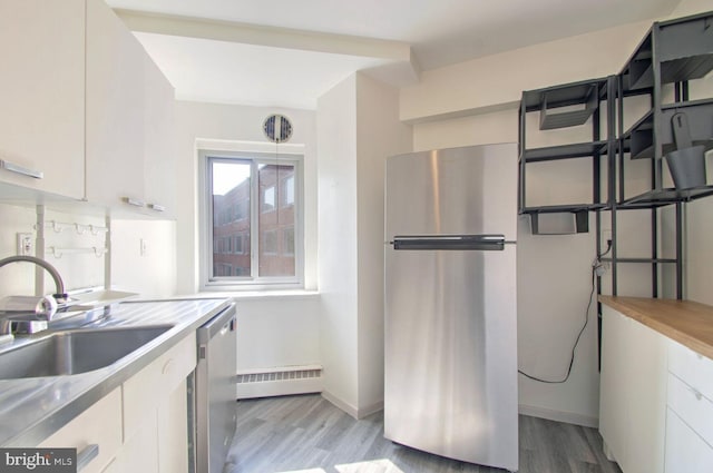 kitchen featuring appliances with stainless steel finishes, a baseboard heating unit, white cabinets, light wood-type flooring, and sink