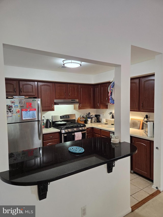 kitchen with a breakfast bar area, stainless steel appliances, and light tile patterned flooring