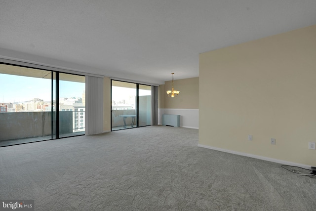 carpeted spare room with an inviting chandelier and radiator heating unit