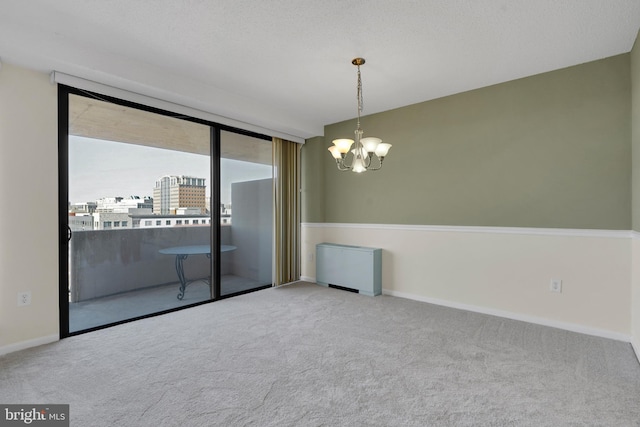 spare room with carpet floors, a textured ceiling, and a notable chandelier