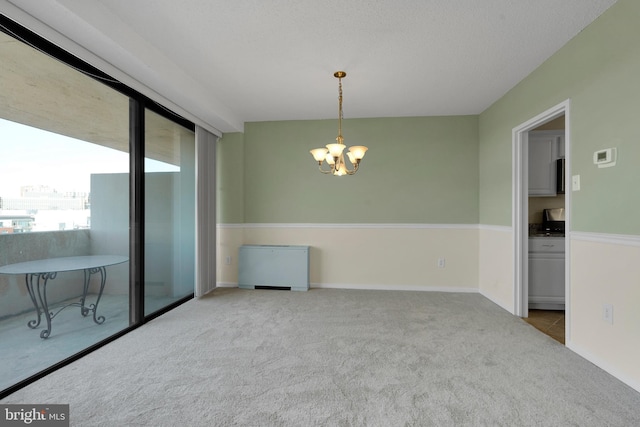 spare room featuring a notable chandelier and light colored carpet