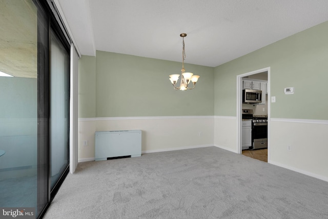 carpeted spare room featuring an inviting chandelier