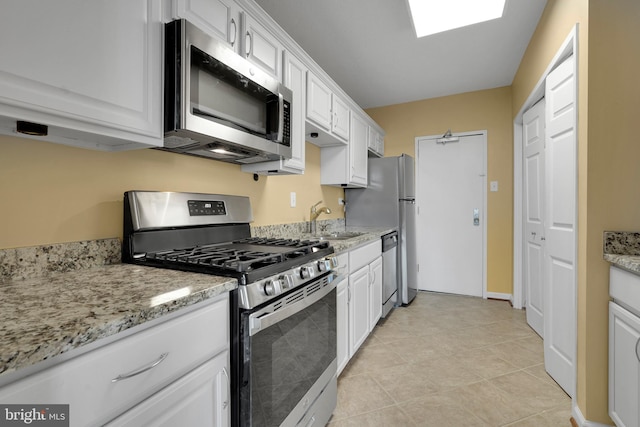 kitchen with appliances with stainless steel finishes, light stone countertops, sink, and white cabinets