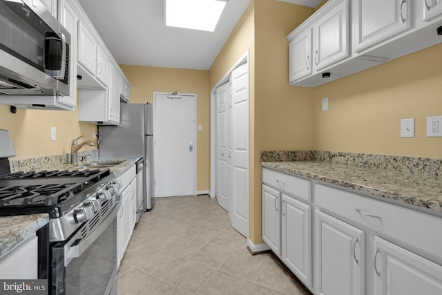 kitchen with appliances with stainless steel finishes, white cabinets, and light stone counters