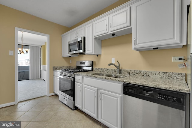 kitchen with appliances with stainless steel finishes, sink, white cabinets, a chandelier, and light tile patterned floors