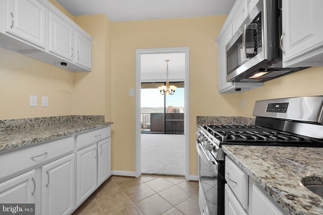 kitchen with white cabinetry, a chandelier, light tile patterned floors, light stone counters, and stainless steel appliances