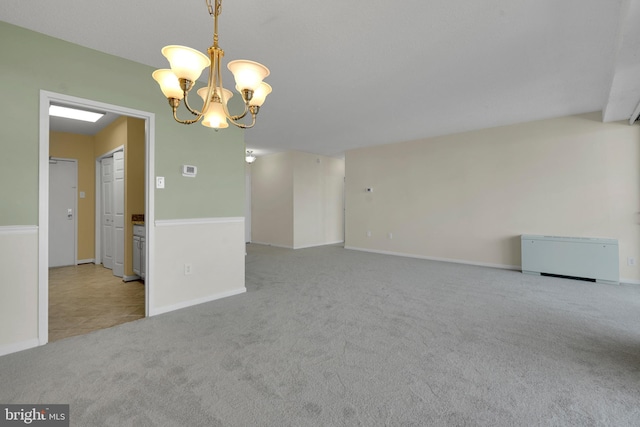 carpeted empty room featuring a notable chandelier