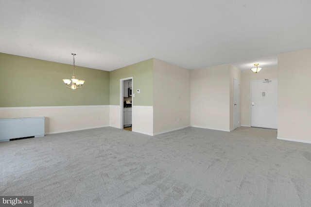 carpeted spare room with an inviting chandelier