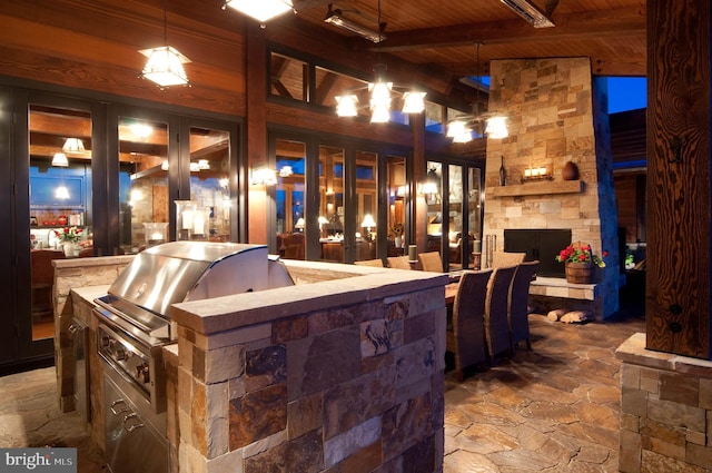 interior space with a stone fireplace, a bar, and area for grilling