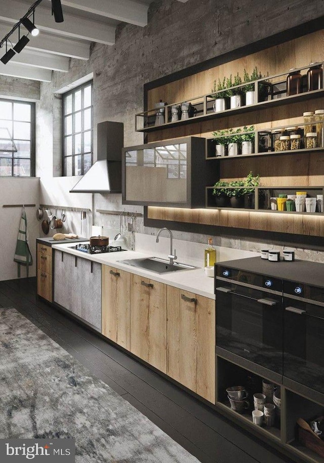 kitchen featuring sink, black gas cooktop, dark wood-type flooring, wall chimney range hood, and beamed ceiling