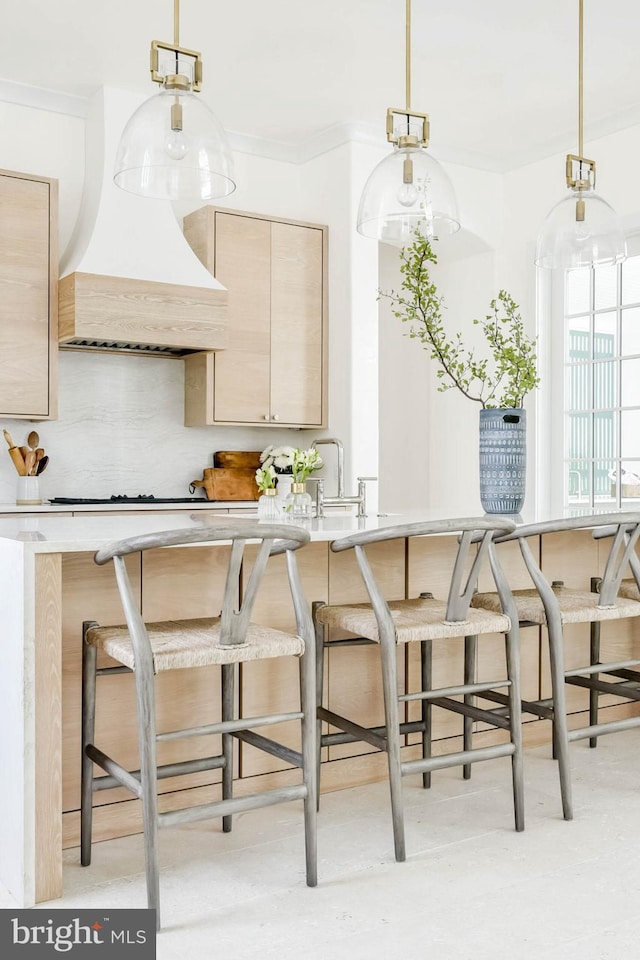 kitchen featuring pendant lighting, stovetop, light brown cabinets, and custom exhaust hood