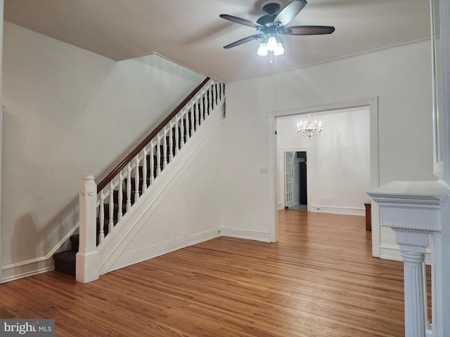 stairs with hardwood / wood-style flooring and ceiling fan with notable chandelier