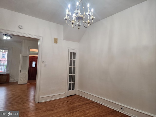 unfurnished room featuring hardwood / wood-style flooring, a chandelier, and lofted ceiling