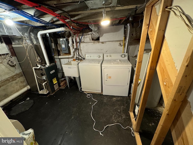 basement featuring sink, separate washer and dryer, electric panel, and heating unit