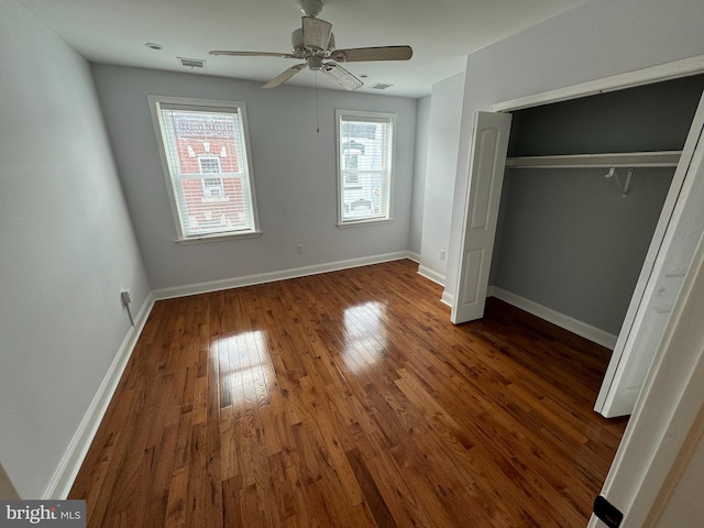 unfurnished bedroom with ceiling fan, dark wood-type flooring, and a closet