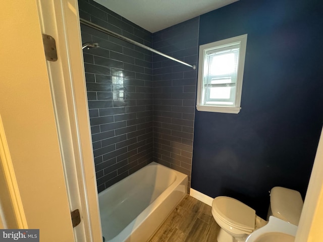 bathroom featuring toilet, tiled shower / bath combo, and wood-type flooring