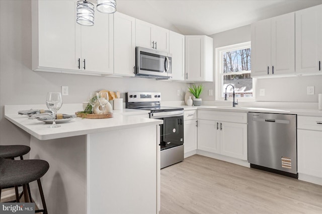 kitchen featuring stainless steel appliances, a breakfast bar, sink, and white cabinets