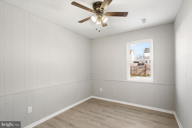 empty room with ceiling fan and light hardwood / wood-style flooring